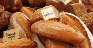 Allée de supermarché en journée avec étagères et mains anonymes cherchant des produits