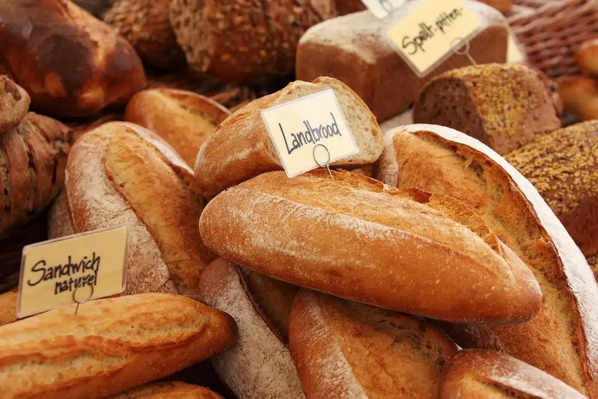 Allée de supermarché en journée avec étagères et mains anonymes cherchant des produits