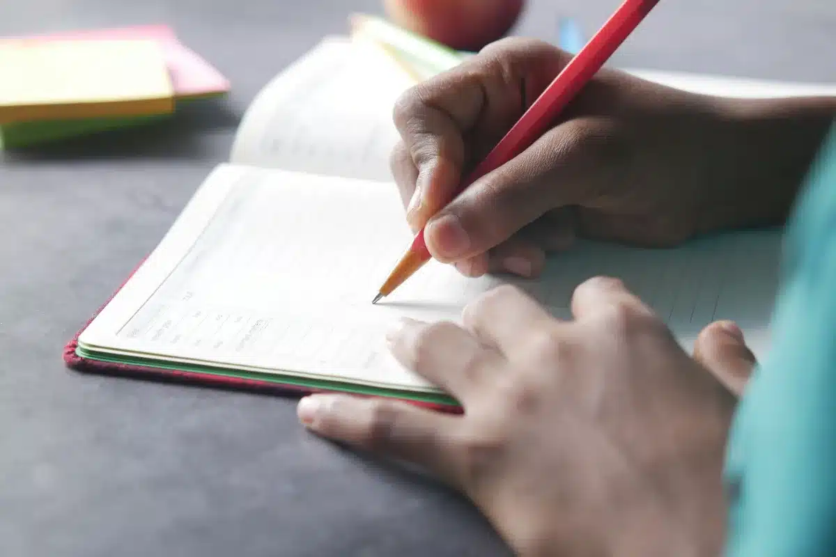 Personne écrivant dans un carnet pour noter ses réussites